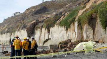 RUNTUH: Beberapa anggota kecemasan meninjau runtuhan cerun di sebuah pantai di Encinitas, California, AS kelmarin. — Gambar Reuters