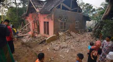 MUSNAH: Penduduk kampung melihat kerosakan sebuah rumah di Pandeglang, wilayah Banten semalam selepas gempa bumi kuat melanda kawasan itu. — Gambar AFP