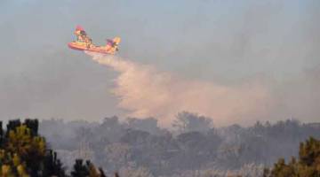 MALANG TIDAK BERBAU: Sebuah pesawat bomba Canadair  Securite Civile menggugurkan air untuk memadam kebakaran di kawasan desa berhampiran Generac, selatan Perancis kelmarin. Seorang juruterbang maut selepas pesawatnya terhempas kelmarin manakala api memusnahkan 130 hektar lagi kawasan hutan dan kebun anggur sekitar Generac dalam daerah Gard. — Gambar AFP