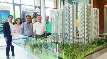 JOHN (dua kanan) dan beberapa kakitangan Hap Seng yang lain merakam gambar kenangan dekat replika model bangunan kondominium Kingfisher Inanam.