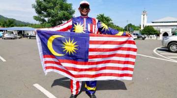 BANGGA: Rahman menggayakan baju Melayu yang direka menggunakan Jalur Gemilang di pekarangan Dewan Tun Hamdan, Tamparuli semalam. — Gambar Bernama 