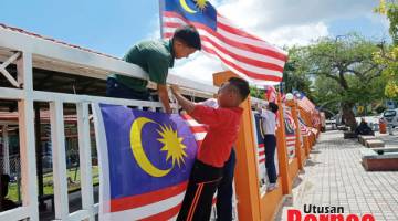 SEKOLAH: Pelajar turut bersama memasang bendera.