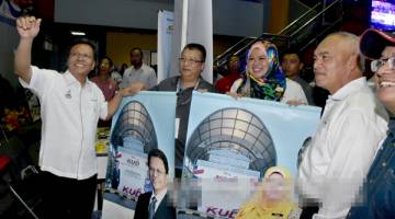 BERI SOKONGAN: Shafie (kiri) merakam gambar kenangan bersama tetamu kehormat yang lain sambil memegang kain rentang promosi KUD pada Majlis Perasmian KUD Zon Sabah.