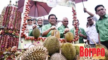 DURIAN: Shafie (tiga kiri) bersama Yusof (tengah), isteri Ketua Menteri Datin Seri Shuryani Shuaib (dua kiri) dan tetamu undangan lain menunjukkan buah durian semasa melawat tapak pameran festival itu.