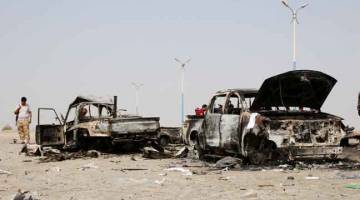 TIADA KESUDAHAN: Pejuang pemisah selatan Yaman memeriksa bangkai kenderaan tentera kerajaan yang musnah dalam serangan udara UAE berhampiran Aden, Yaman kelmarin. — Gambar Reuters 