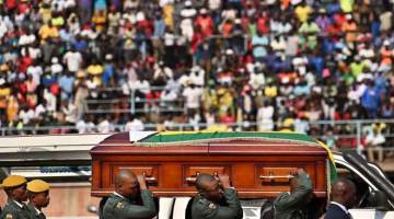 PENGHORMATAN TERAKHIR: Anggota tentera mengusung keranda mengandungi jasad Mugabe tiba di stadium bersejarah Rufaro di Harare, Zimbabwe kelmarin. — Gambar AFP