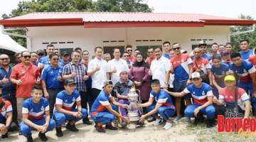 KENANGAN: Peter dan tetamu kehormat lain serta anggota skuad Tambadau Sabah bergambar dengan Paulus (duduk di kerusi roda) dan Piala Liga Premier.