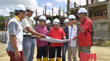 PANTAU: Samsuni dan Ruji melihat lakaran projek ketika membuat lawatan di tapak pembinaan bersama kontraktor serta pihak terlibat.