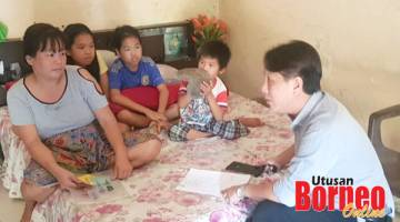 LAWAT: Amsi (kanan) ketika melawat sebuah keluarga susah yang tinggal di bilik terbiar di Sandakan.