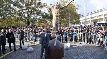 BANGGA: Ibrahimovic memberikan ‘pose’ istimewa di hadapan patung gangsa tersebut pada majlis perasmian berhampiran stadium di Malmo, Sewden kelmarin. — Gambar AFP