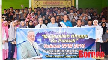KENANGAN: Arifin merakamkan gambar kenangan bersama calon SPM di SMK Membakut.