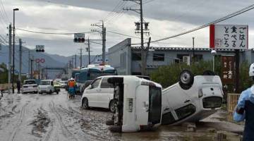 KOTOR: Kenderaan terbalik tersadai di sebatang jalan yang berlumpur sejurus kemaraan Taufan Hagibis di Nagano, semalam. — Gambar AFP