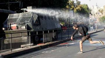 GANAS: Penunjuk perasaan bertempur dengan polis rusuhan semasa bantahan ganas terhadap peningkatan harga tiket metro             di pusat bandar Santiago, Chile kelmarin. — Gambar Reuters