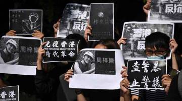 PROTES: Sekumpulan pelajar Universiti Sains dan Teknologi Hong Kong memegang gambar               Chow ketika menyertai rali antikerajaan di Hong Kong, China semalam. — Gambar Philip Fong/AFP