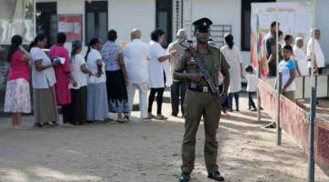 KAWALAN KETAT: Anggota polis berkawal ketika orang ramai berbaris untuk membuang undi dalam pilihan raya presiden  di Colombo, Sri Lanka semalam. — Gambar Reuters 