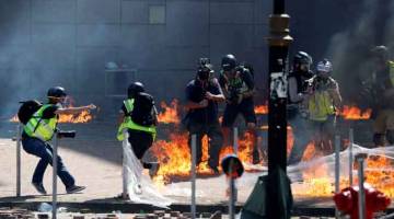 DEMI TUGAS: Para wartawan dan jurugambar terkejut apabila dilontar dengan koktel Molotov ketika penunjuk perasaan bertelingkah dengan polis antirusuhan di luar PolyU di Hong Kong, semalam. — Gambar Reuters