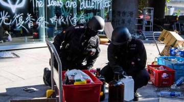 BERHATI-HATI: Anggota polis dari unit Biro Pelupusan Bahan Letupan (EOD) dengan berhati-hati memeriksa untuk bahan letupan dan kimia di kampus Universiti Politeknik Hong Kong di daerah Hung Hom di Hong Kong, China semalam. — Gambar Anthony Wallace/AFP