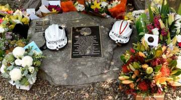 PENGHORMATAN: Helmet dan bunga diletakkan di atas memorial untuk dua anggota bomba yang terbunuh semasa menangani kebakaran belukar di Horsley Park, New South Wales, Australia semalam. — Gambar Reuters