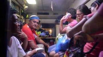 PADAT: Para penduduk yang mengadu sakit perut selepas meminum ‘lambanog’ buatan tempatan duduk di dalam ambulans ketika menunggu untuk dipindahkan dari Hospital Umum Filipina (PGH) ke sebuah hospital lain di Manila, kelmarin. — Gambar AFP