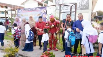 MESRA: Para guru bersama maskot adiwira Iron Man menyambut kehadiran murid-murid pada hari pertama persekolahan.