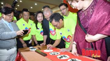TANDATANGAN: Shafie (dua kanan) menurunkan tandatangan di atas kertas kaligrafi Cina pada majlis itu sambil diperhatikan oleh tetamu jemputan lain.