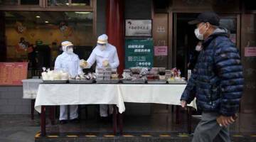 SENGSARA: Para pekerja restoran memakai sut penuh sebagai langkah pencegahan terhadap jangkitan COVID-19 ketika menjual makanan di pekarangan premis mereka di Beijing, baru-baru ini. — Gambar AFP