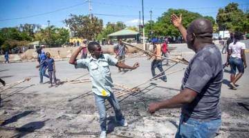 MASIH KACAU: Gambar fail 18 Februari menunjukkan orang ramai membersihkan kawasan Champ de Mars di Port-au-Prince selepas anggota kesatuan polis yang mengadakan tunjuk perasaan bertindak membakar gerai-gerai karnival sehari sebelumnya. — Gambar AFP