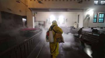 DISINFEKTAN: Seorang pekerja kesihatan menyembur bahan disinfektan di sebuah gereja                     di bandar Wuhan, wilayah Hubei, China kelmarin. — Gambar AFP