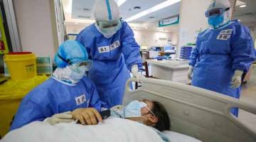 DALAM BAHAYA: Para doktor menenangkan seorang wanita hamil yang dijangkiti COVID-19 sebelum menjalani pembedahan caesarean di wad isolasi ginekologi dan obstetrik di Hospital Xiehe di Wuhan, wilayah tengah Hubei kelmarin. — Gambar AFP