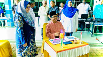 RASMI: Raisin Saidin menandatangani buku perasmian PIBG disaksikan oleh YDP PIBG Rohana Yasin (kanan) dan Guru Besar SKPD Hajah Dayang Damit.