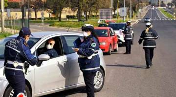 SEKATAN: Anggota Polis Tempatan Rom membuat semakan dokumen pengesahan ke atas pengguna jalan raya di Via Pontina, di Rom, kelmarin ketika negara tersebut menguatkuasakan ‘lockdown‘ bagi menghentikan penyebaran  COVID-19. — Gambar  AFP