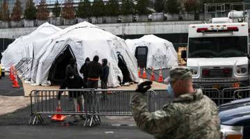 RUMAH MAYAT: Pekerja dan anggota Pengawal Negara membina rumah mayat sementara di luar Hospital Bellevue di New York, kelmarin. Bilangan kematian di AS akibat COVID-19 melonjak melepasi 1,000, dengan 68,000 jangkitan yang disahkan. — Gambar AFP