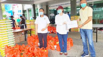 SERAH: Christina (tengah) menyerahkan bantuan makanan kepada Kapitan Cina Stanley Yong,  turut kelihatan ialah Nordin (kiri).