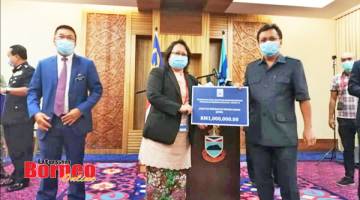 SUMBANGAN: Shafie (kanan) menyampaikan sumbangan bernilai RM1 juta kepada Pengarah Kesihatan Negeri Sabah Datuk Dr Christina Rundi, turut kelihatan ialah Setiausaha Kerajaan Negeri Datuk Safar Untong (kiri).