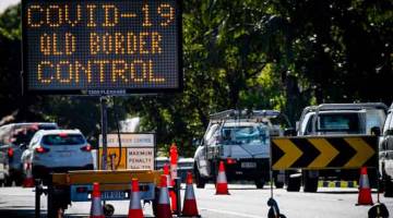 TEGAS: Papan tanda mengenai sekatan perjalanan dalam menangani COVID-19 dapat dilihat di Lebuh Raya Pasifik di sempadan Queensland-New South Wales di Brisbane. — Gambar AFP