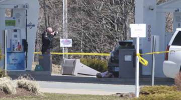 SERANGAN KEJAM: Seorang anggota unit forensik RCMP mengambil gambar di tempat kejadian susulan amukan bersenjata dekat Big Stop berhampiran Elmsdale, Nova Scotia kelmarin. — Gambar AFP