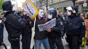 TEGAS: Anggota polis bertelingkah dengan seorang penunjuk perasaan antisekatan COVID-19 di Berlin, kelmarin.  — Gambar AFP