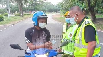 PERIKSA: Mohd Azhar memeriksa penunggang motorsikal yang melalui Sekatan Jalan Raya.