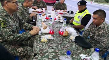 BERBUKA: Hafiz dan Al-Hambra berbuka puasa dengan petugas SJR di Jalan Kuil Lok Kawi di sini semalam.