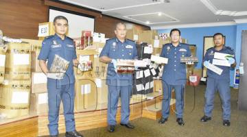 ROKOK SELUDUP: Ketua JKDM Daerah Lahad Datu Saidin Jalaluddin (dua dari kiri) bersama pegawainya menunjukkan sebahagian rampasan rokok seludup.