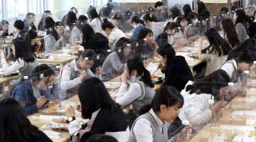 PENCEGAHAN: Para pelajar terpisah oleh skrin pelindung sebagai langkah pencegahan COVID-19 ketika makan tengah hari di kantin sekolah tinggi di daerah Daejeon, Korea Selatan semalam. — Gambar AFP