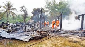 MUSNAH: Pasukan bomba memeriksa kawasan kejadian bagi memastikan kebakaran terkawal sepenuhnya.