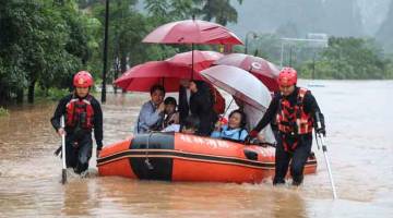 PINDAH: Gambar diambil pada 7 Jun menunjukkan anggota penyelamat memindahkan penduduk di kawasan dilanda banjir selepas hujan lebat di Yangshuo, wilayah Guangxi di selatan China. — Gambar AFP