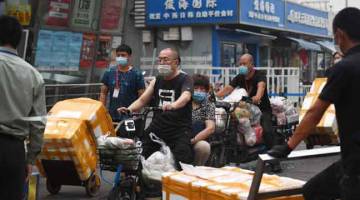 DITUTUP: Orang ramai membawa keluar stok jualan dari pasar makanan laut Jingshen di Beijing pada Sabtu. Pasar berkenaan telah ditutup untuk disinfeksi dan siasatan pada Jumaat setelah mangsa baharu positif koronavirus mengunjungi pasar basah berkenaan. — Gambar AFP