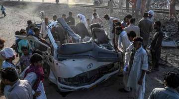 REMUK: Penduduk berkumpul di sekeliling van yang remuk selepas dilanggar oleh sebuah kereta api di kawasan Farooqabad di daerah Sheikhupura, wilayah Punjab, Pakistan kelmarin. — Gambar AFP 