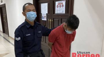Tertuduh diiringi pegawai polis di lobi Kompleks Mahkamah Kuching, hari ini. 