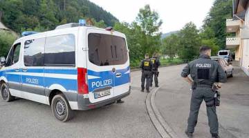 SUSPEK BERBAHAYA: Polis berdiri berhampiran tempat suspek yang bersenjata penuh, Yves Rausch disyaki bersembunyi dalam gambar yang dirakam kelmarin.  — Gambar AFP