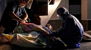 DITEMUI MATI: Pekerja kesihatan memakai pelitup muka untuk melindungi diri daripada                 COVID-19 memeriksa mayat seorang lelaki yang ditemui di tepi jalan di Cucuta, Colombia kelmarin. Colombia kini mencatatkan lebih 7,000 kematian akibat penularan virus itu sejak ia bermula empat bulan setengah. — Gambar AFP