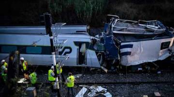 REMUK: Anggota keselamatan memeriksa bangkai kenderaan penyelenggaraan landasan kereta api dan kereta api berkelajuan tinggi (kanan) selepas pertembungan di Soure, berhampiran Coimbra kelmarin. — Gambar AFP