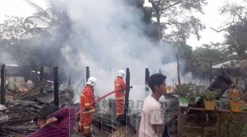 MUSNAH: Anggota bomba sedang memadam kebakaran rumah di Kampung Maliau.